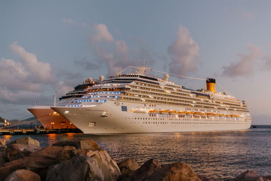 A cruise ship docked at sunset with its cabin lights glowing
